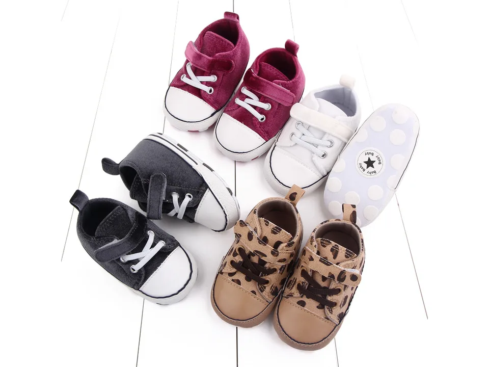 A collection of toddler sneakers in various colors and patterns including leopard print, grey, white, and maroon.