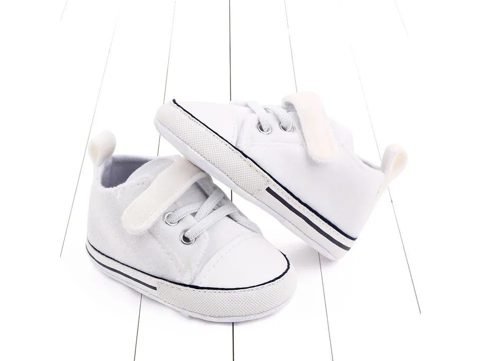 A pair of white toddler sneakers shown from the side.