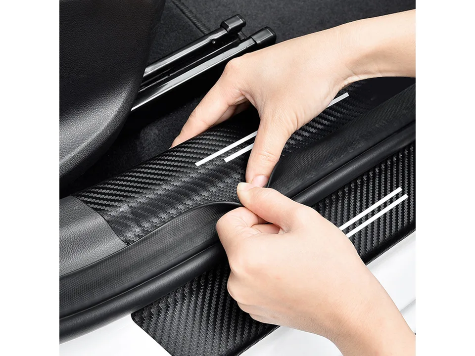 Close-up of hands peeling the backing off a carbon fiber style door sill protector.