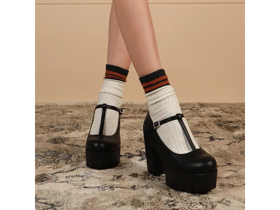 A person wearing black T-strap platform heels with striped socks.