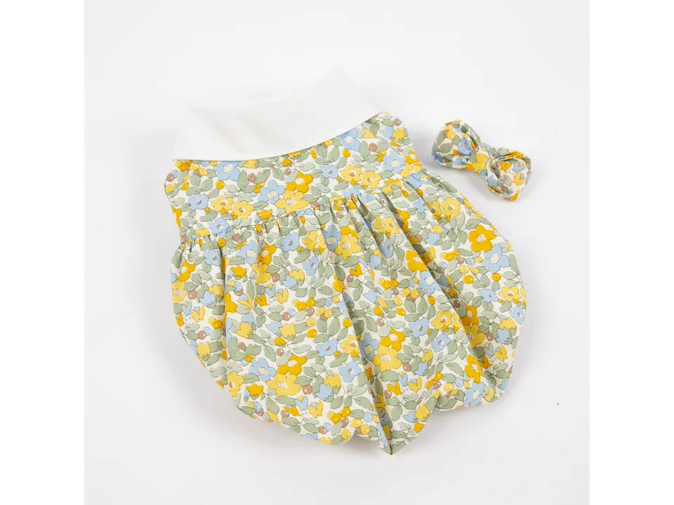 A yellow floral dog dress with a white collar and a matching hair bow.