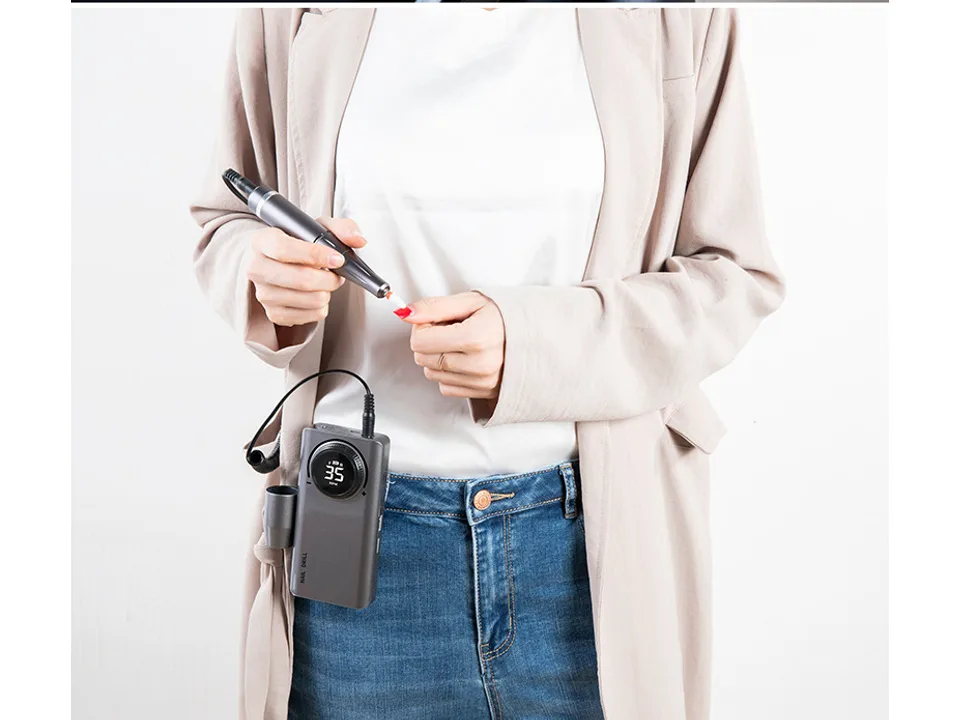 Person using the nail drill on their fingernail.