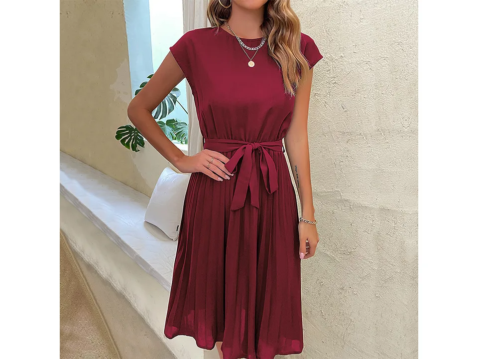 A woman wearing a dark red pleated midi dress with a tie waist.