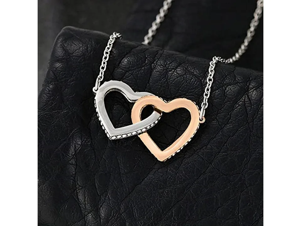 Close-up of the interlocking silver and rose gold heart pendant on a chain.