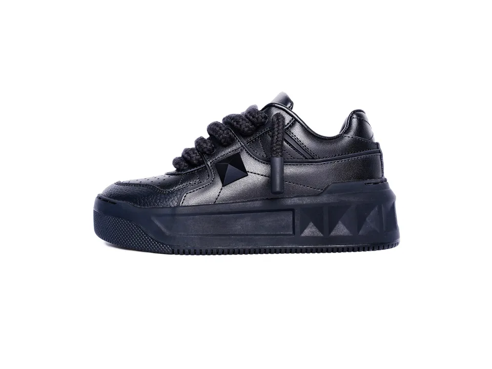 Side view of a black platform sneaker with a rivet detail.