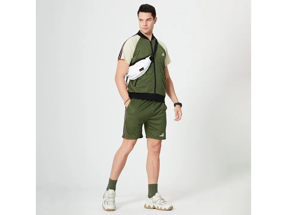 A man wearing a green and beige athletic short sleeve top and matching shorts.