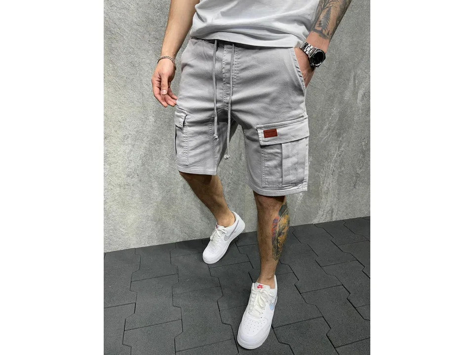 Man wearing grey cargo shorts with side pockets and a drawstring waist.