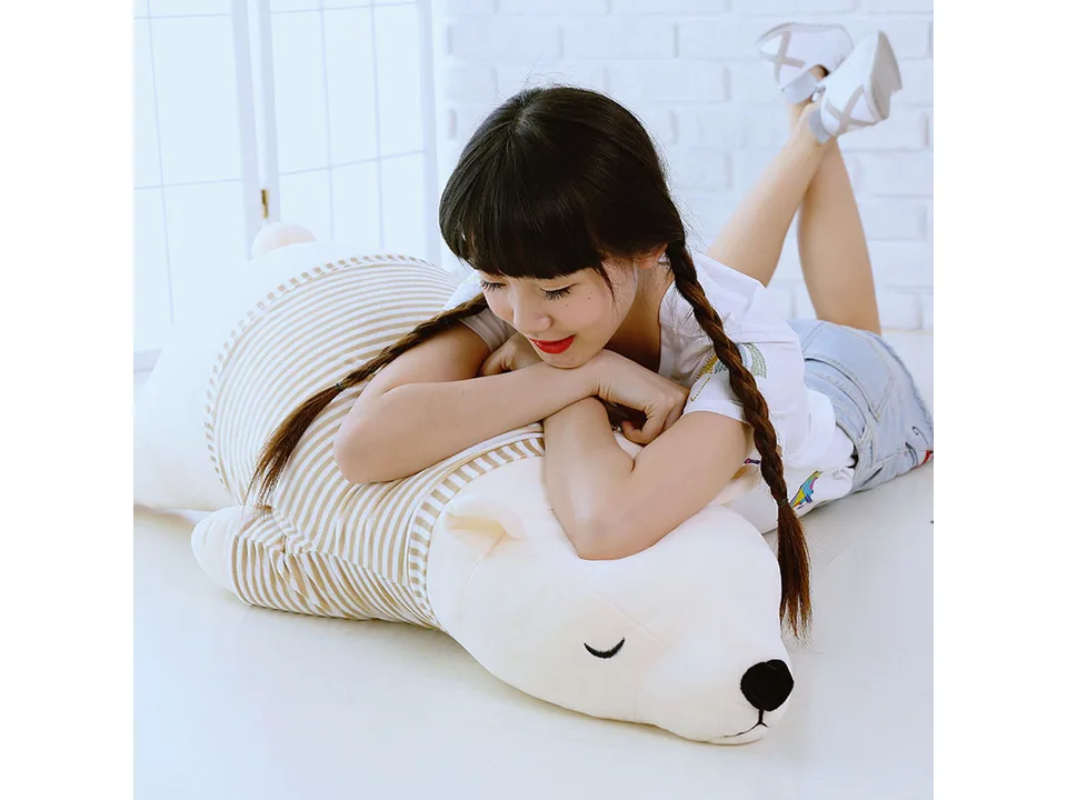 A young woman lying on her stomach, resting her head on the large polar bear plush pillow.