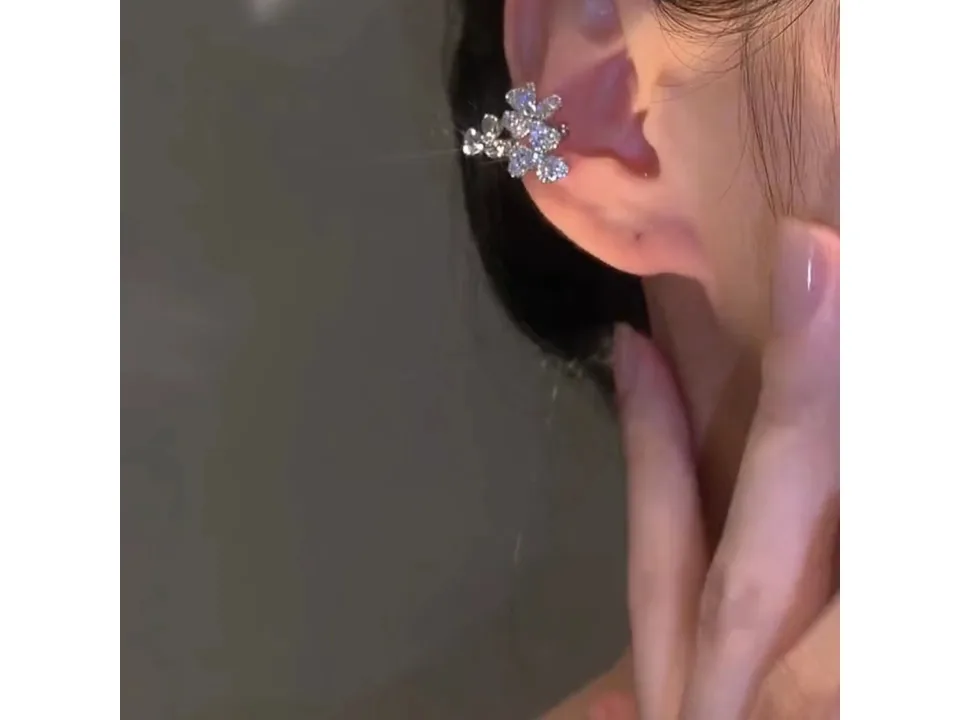 A sparkling flower-shaped ear cuff worn on the ear.