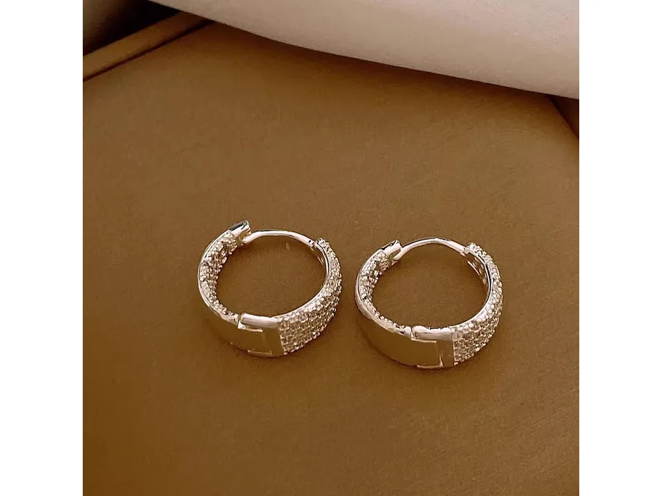 A pair of silver-tone hoop earrings showing the clasp mechanism.