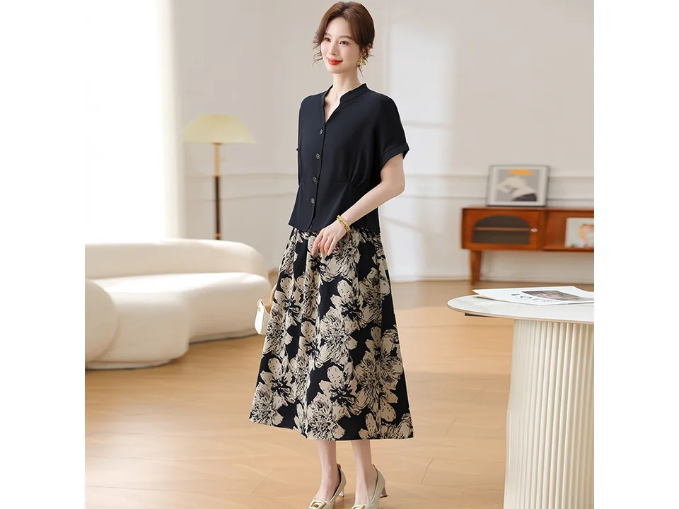 A model standing in a room wearing a black shirt and floral skirt set.