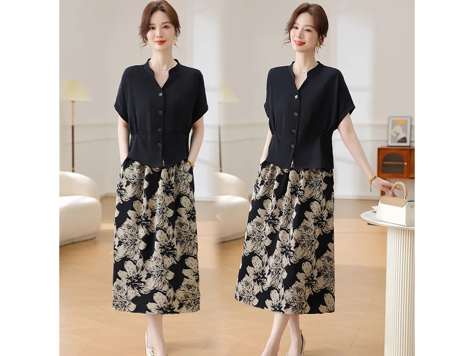 A model wearing a black shirt and floral skirt set with her hands in her pockets.