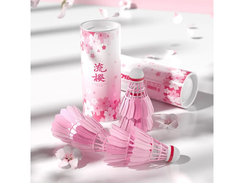Pink badminton shuttlecocks arranged next to their cherry blossom themed tube.