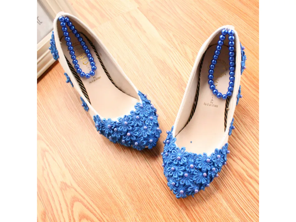 A pair of white high heels with blue floral lace and pearl embellishments, viewed from above.