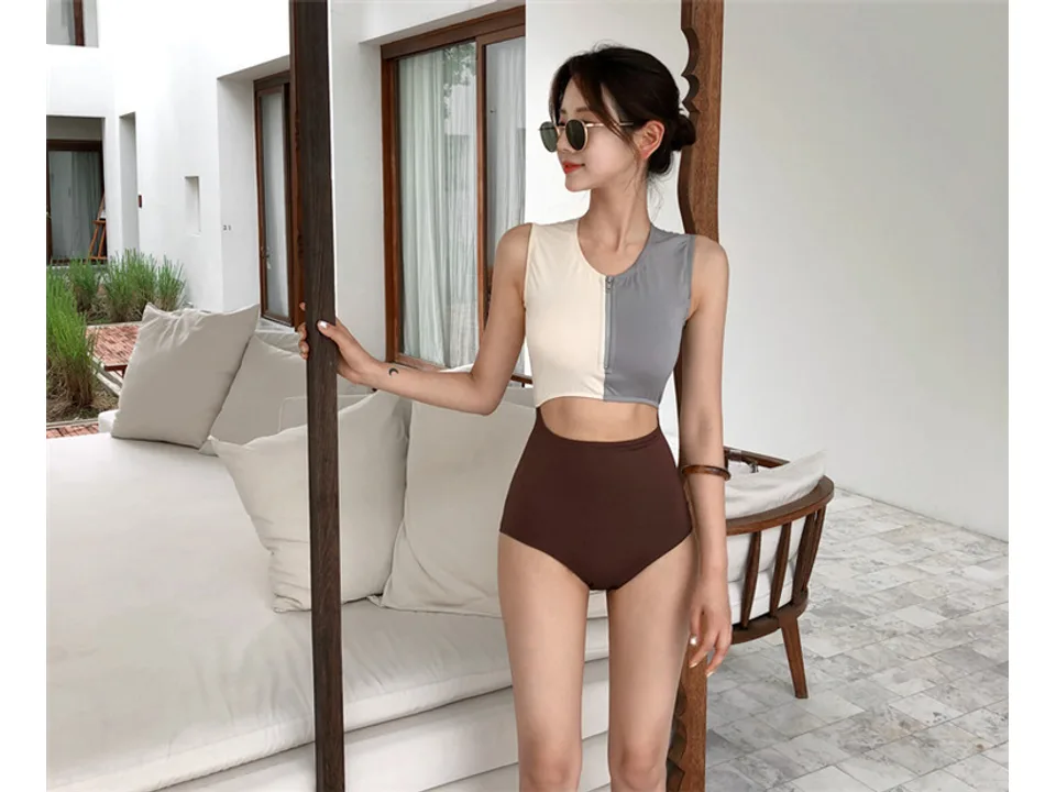 A woman standing and wearing a colorblock cutout one-piece swimsuit.