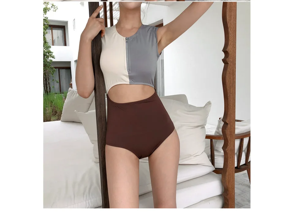 Close-up of a woman wearing a colorblock cutout one-piece swimsuit.