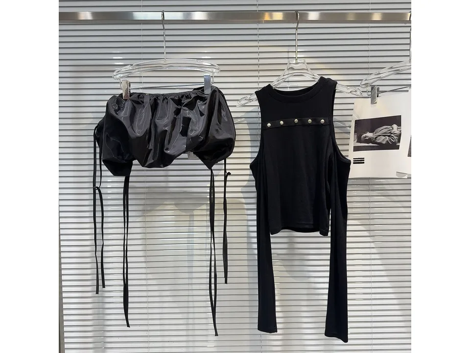 Black long sleeve shirt with detachable lantern overlay hanging on a rack.