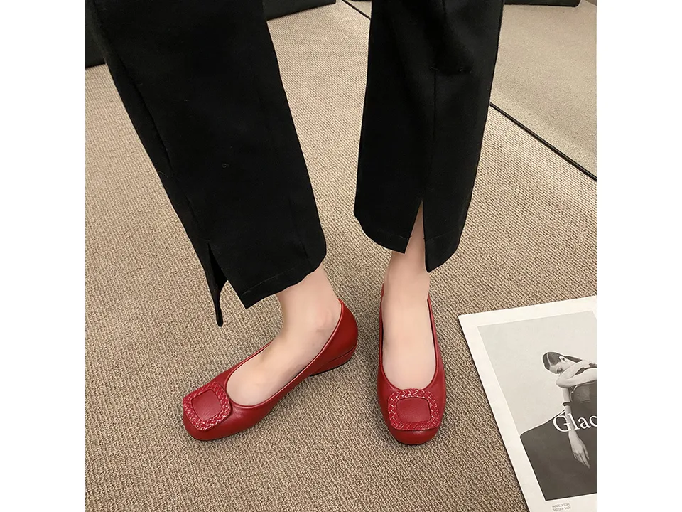A person wearing red low heel pumps with a square buckle detail.