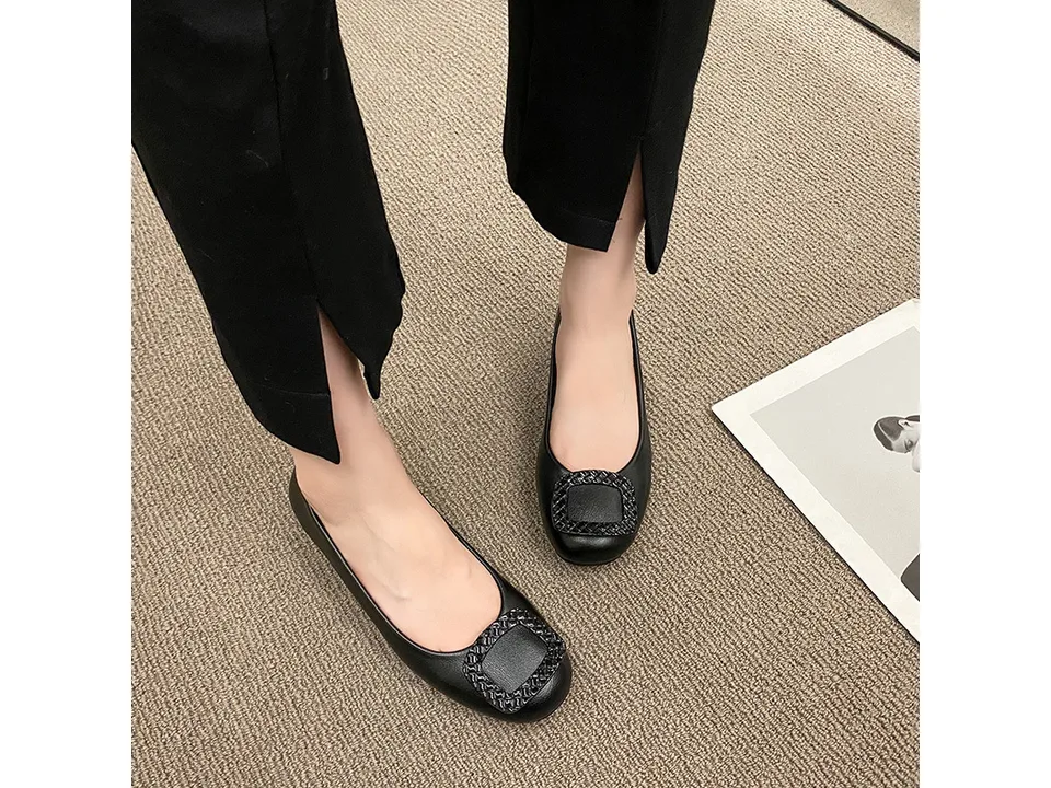 A person wearing black low heel pumps with a square buckle detail.