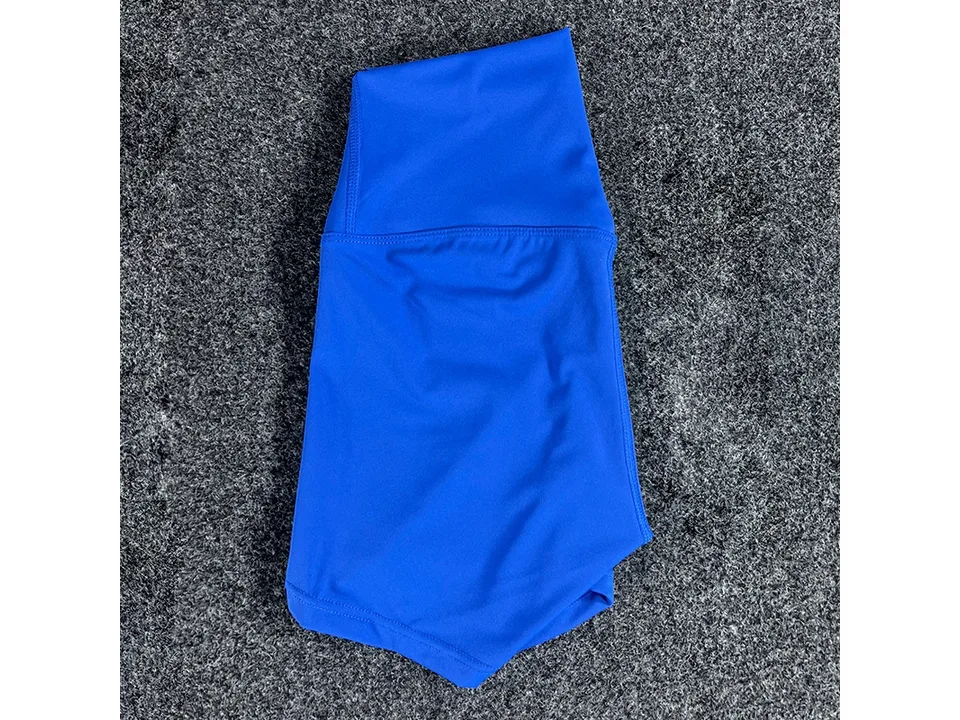 Blue high-waisted yoga shorts folded on a textured surface.