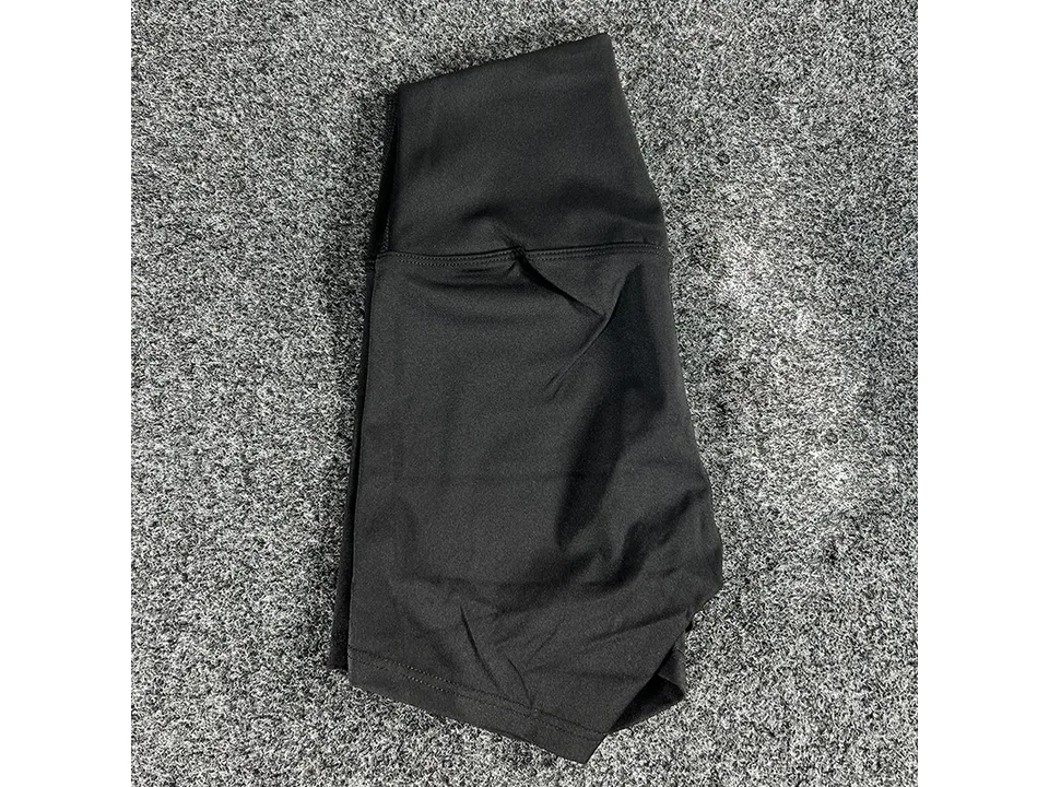 Black high-waisted yoga shorts folded on a textured surface.