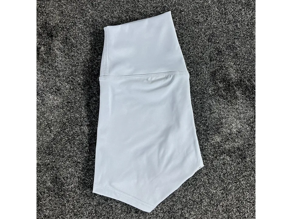 Light grey high-waisted yoga shorts folded on a textured surface.
