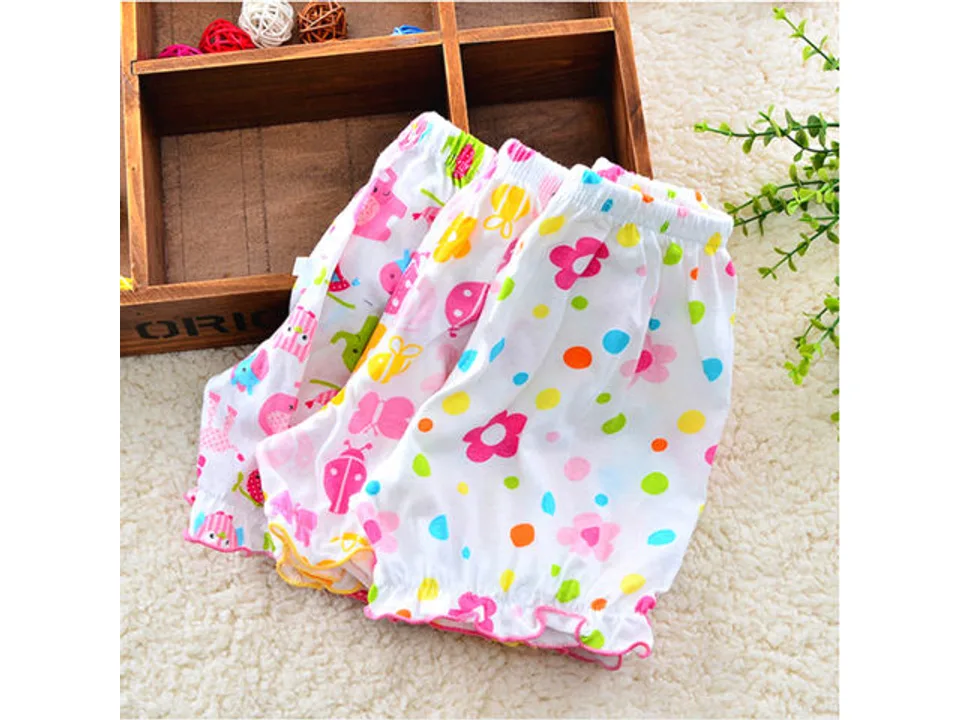 Three pairs of patterned baby bloomer shorts stacked together.