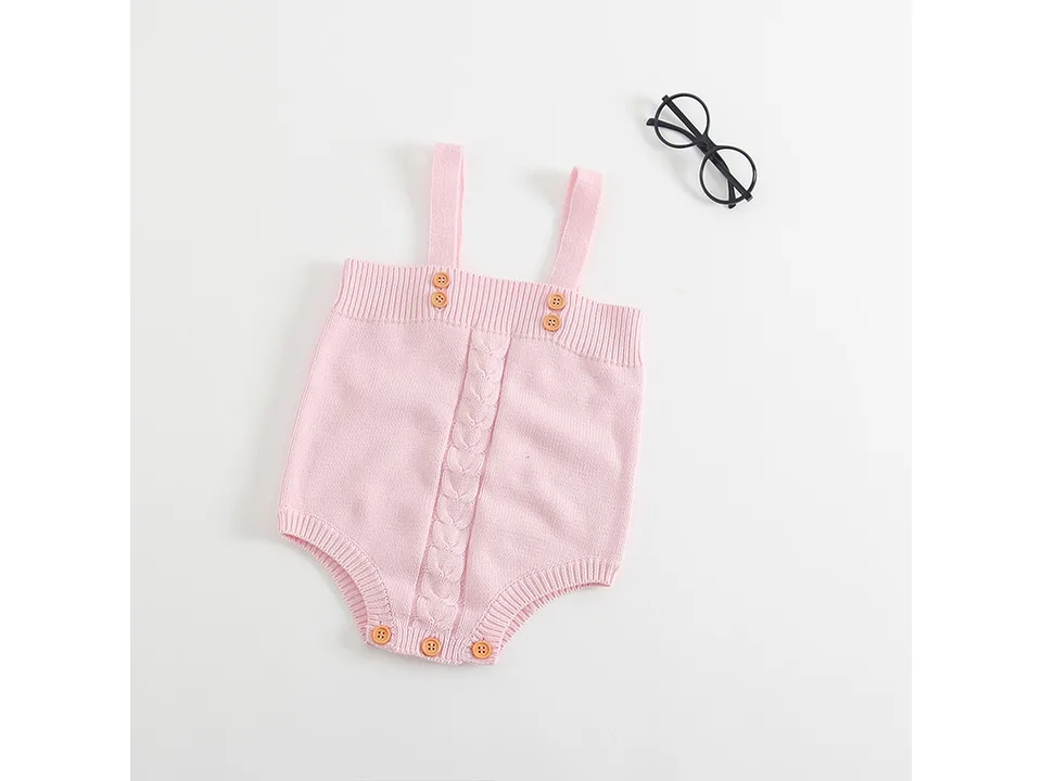 Front view of a pink knitted baby romper with button straps.