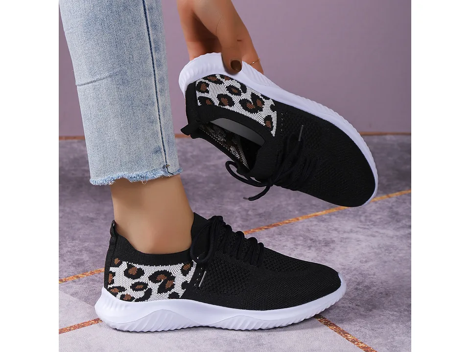 Black leopard print casual sneakers being worn and held.