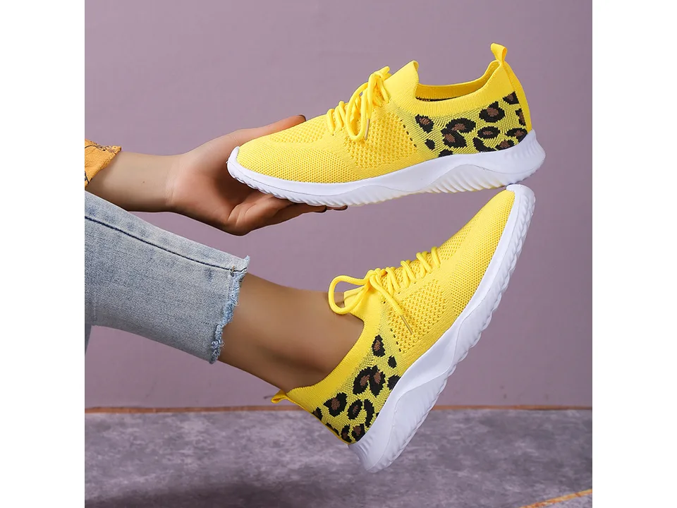 Yellow leopard print casual sneakers being worn and held.
