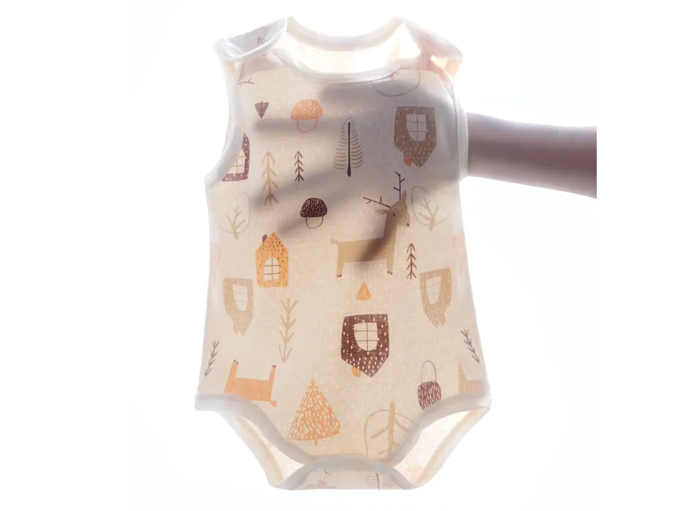 A hand holding up the sleeveless baby romper to show the fabric texture and pattern.