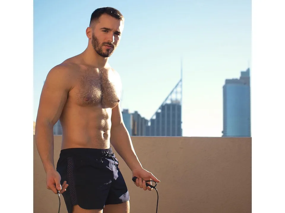 A man exercising outdoors wearing navy blue athletic mesh shorts.