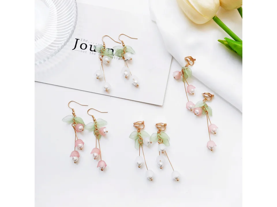 A collection of lily of the valley earrings in pink and white, featuring both hook and clip-on styles.
