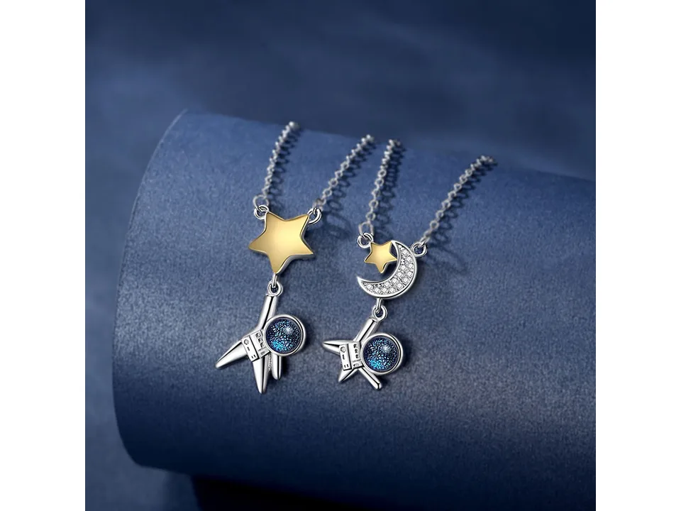 The two astronaut necklaces displayed together on a blue stand.