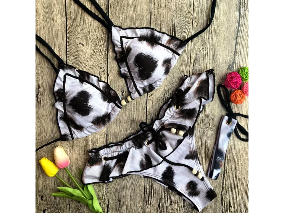 Leopard print bikini set with ruffle trim and beaded details on a wooden surface.