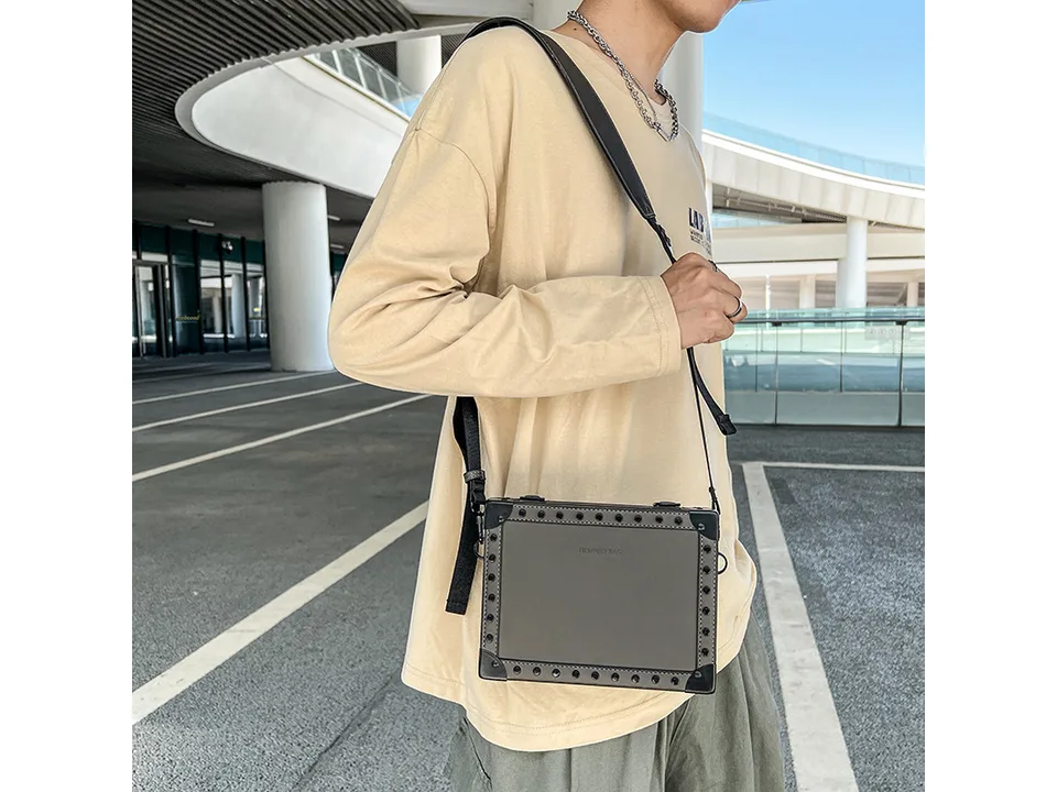 A man wearing a grey square crossbody bag.