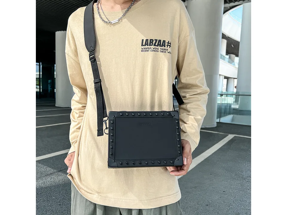 A man wearing a black square crossbody bag.