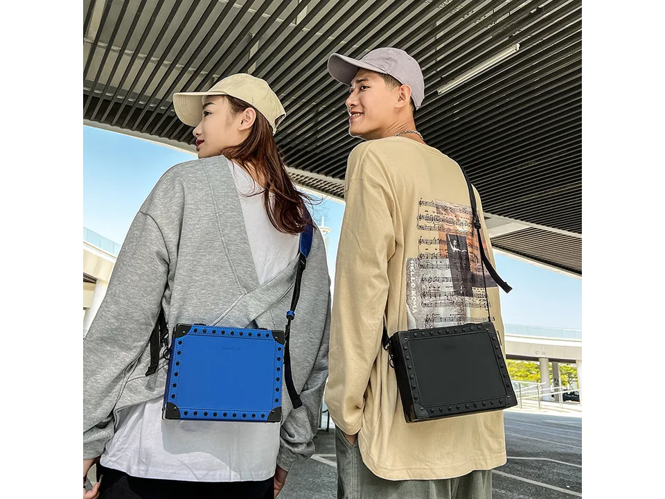 A man and a woman wearing blue and black square crossbody bags.