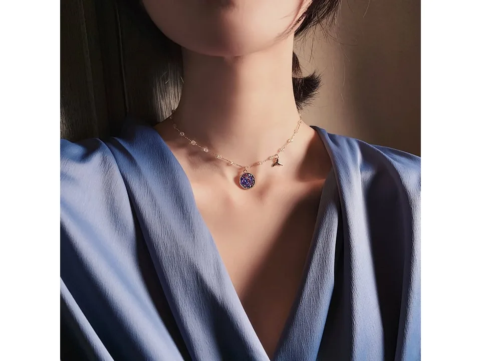 A woman wearing the mermaid necklace with a blue glitter pendant and tail charm.