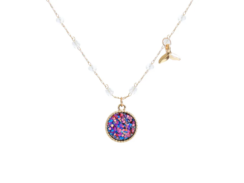 Close-up of the mermaid necklace featuring a round glitter pendant and a small gold tail charm.