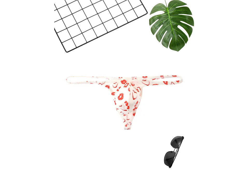 White men's thong with red lip print, displayed with a grid and sunglasses.