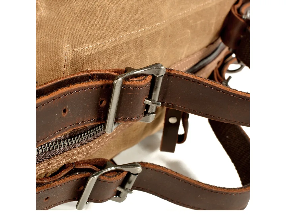 Close-up of the leather straps and metal buckles on the canvas bag.
