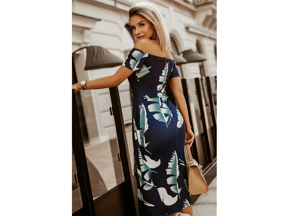 A woman seen from the back wearing a navy blue off-shoulder midi dress with a tropical leaf print.